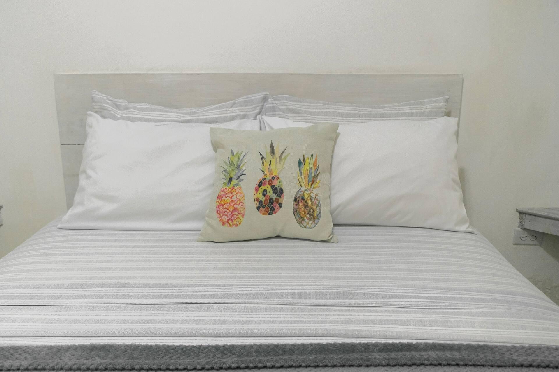 A queen bed made up with pineapple print cushions